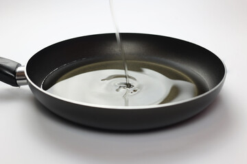 Empty frying pan with oil. Oil is poured into the pan. Close-up of black kitchen utensils. Preparation for frying. Preparing breakfast. Frying pan Black metal utensils. Lots of oil for fries