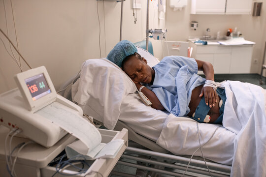 Pregnant black woman touching belly near fetal monitor
