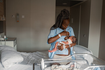 Black mom breastfeeding infant near hospital bed