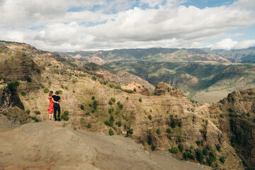 Obraz premium Young female tourist enjoying the view into Waimea Canyon, Kauai, Hawaii