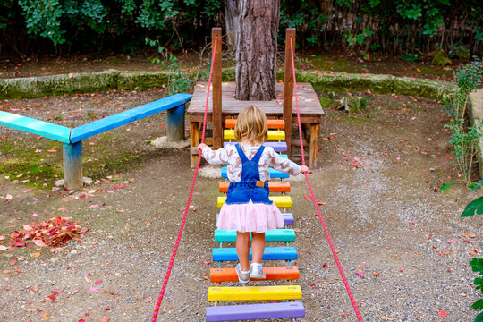 girl walking on a balance log in an outdoor playground in the park 