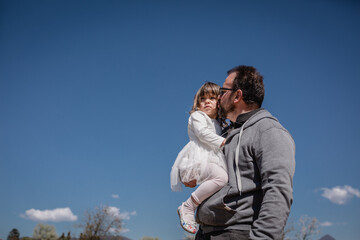 low angle view of Father kissing daughter in white dress