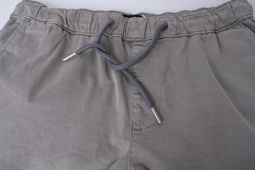 close-up of texture of gray cotton trousers, pants with welt pockets, ankle cuffs, drawstring at...