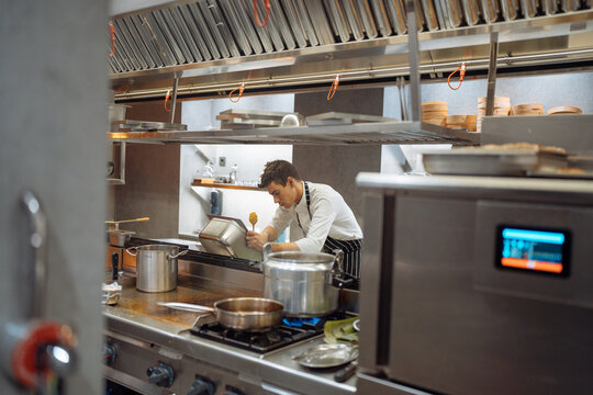 Male chef removing excess sauce from container