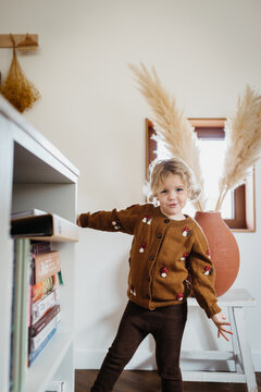 Girl dancing in the kitchen. she is wearing a mushroom cardigan