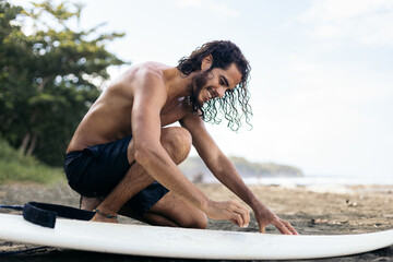 Fototapeta premium Surfer putting surf wax on the board