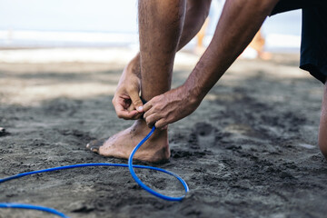 Close up of a man strapping on his surfboard