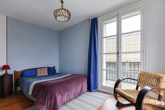 Cosy white bedroom with blue pillow and curtain osier wood chair