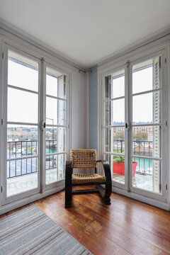 Chair in wicker and wood in between two window doors view to the port