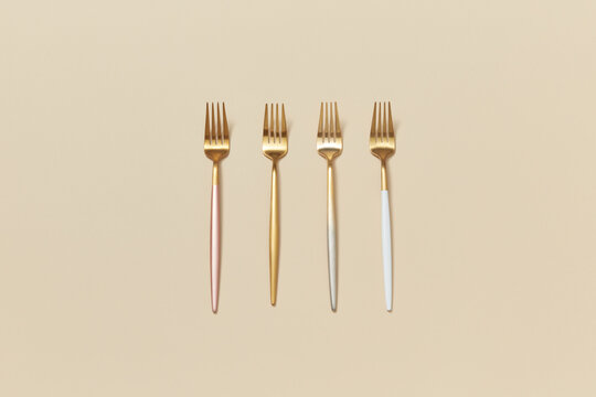 Four trendy chic forks on beige background.