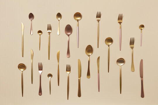 Forks, knives and spoon on beige background.
