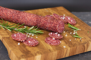Sausage on a wooden board. Sausage with raspberry and salt. Sausage on top. Macro Sausage