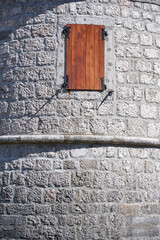 Castle round tower of bricks with lonely window and wooden shutter. Ancient architecture textures