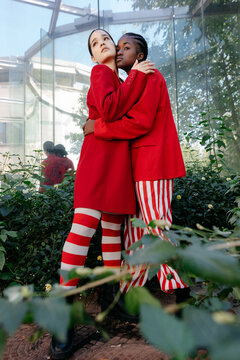 Trendy diverse women embracing in greenhouse