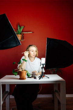 Female vlogger applying makeup during life stream