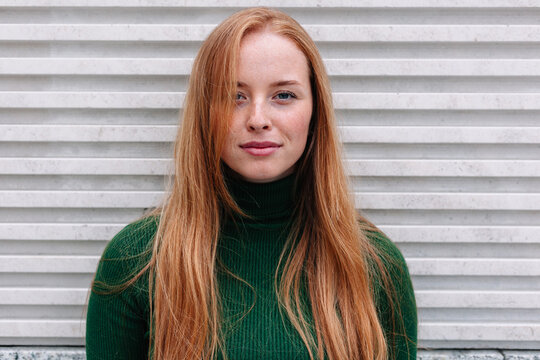 Smiling woman with long red hair on street closeup