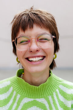 Laughing girl in trendy eyeglasses, fashion makeup and tooth gems