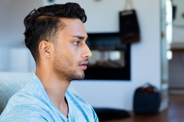 Close up profile of biracial man sitting on floor in bedroom, meditating