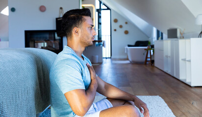 Biracial man sitting on floor in bedroom, meditating