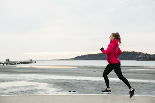 Young woman running in a cold day at the beach