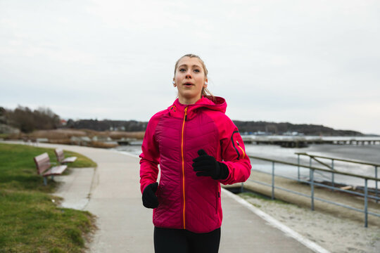 Young woman running in a cold day at the beach