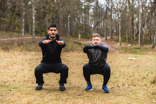Workout partners doing squads outdoors