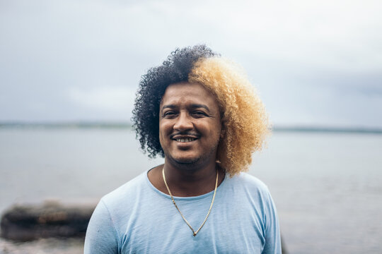 Portrait of a man with colored afro hair on the beach of an island