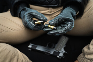 The girl's hands in gloves load 45 caliber cartridges into the magazine from a pistol.