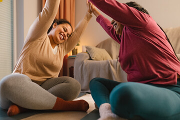 Happy young daughter with her mother doing yoga at home