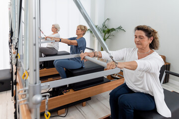 People exercising with trapeze on Pilates reformers