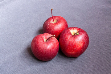 Three red apples on grey