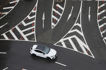 日本の交差点の路面に描かれた通行のマークと白い車の様子