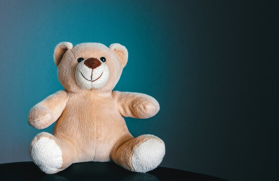 kinder spielzeug teddybär sitzt fröhlich auf bei blauen hintergrund und lächelt
