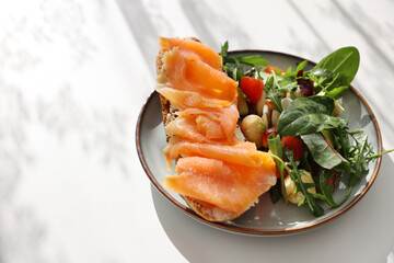 Open sandwich or toast. Grain bread with salmon, salad from avocado, ruccola and mozarella cheese. Healthy snack, fat and omega 3 source copy space white background top view copy space
