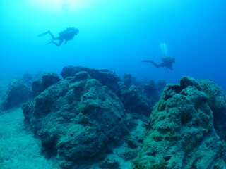 scuba divers underwater exploring reefs 