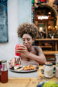 Cuban woman adding ketchup to burger