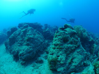 scuba divers underwater exploring reefs 