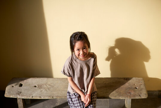 Asian girl resting on a bench in the aisle under sunlight