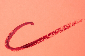 Brush strokes of red paint on peachy pink background, lipstick marks on paper