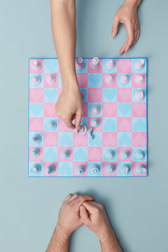 Couple playing chess on board with heart pattern.