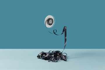 Black cassette tape with hanging round reel.
