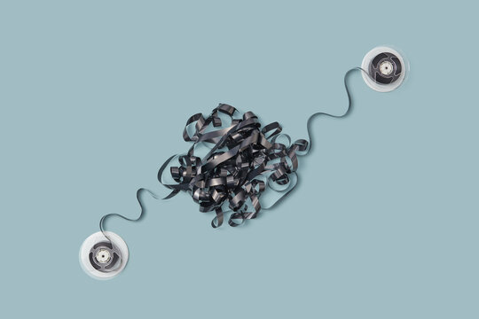Tangled black cassette tape with two round reels.