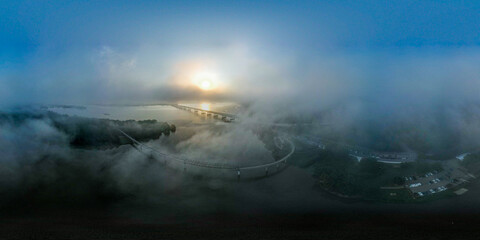 Skyview of bridge passing through clouds and a sunrise
