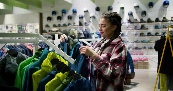 Woman in outdoor clothing store chooses wind down jackets