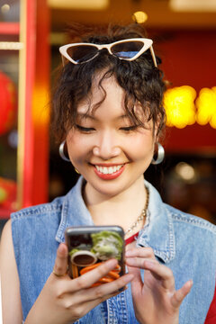 Cheerful woman sending text message using mobile phone 