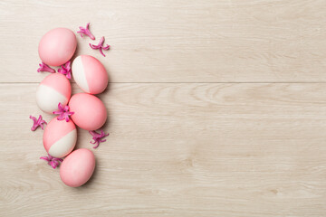 Pink Easter eggs with decor on wooden background, top view