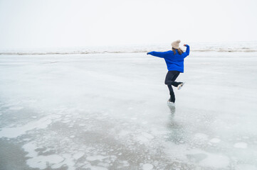 Caucasian woman in a blue sweater skating on a frozen lake. 