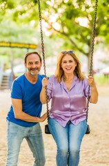 50-59 years senior happiness relationship. Hispanic family enjoy life couple with a swing in a park