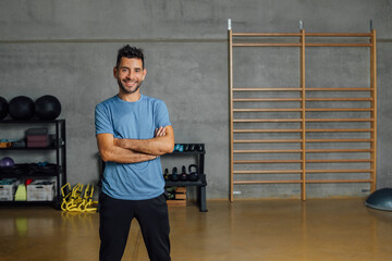 Portrait of Confident smiling hispanic man looking at camera in sport club. Fitness instructor...