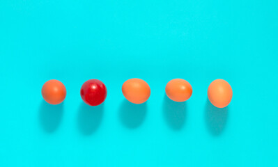 Holiday concept with arranged eggs in a line. Minimal Easter idea with red egg on blue background. Flat lay.